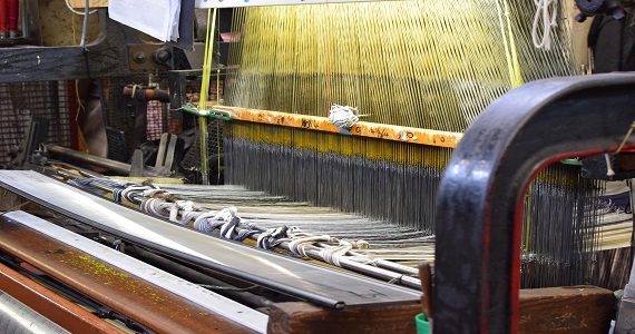 Image of a wood machine resembling a loom processing threads.